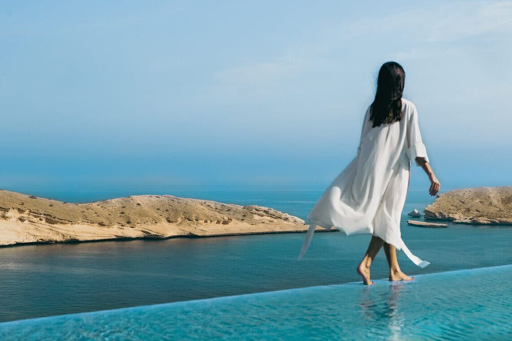An infinity pool at Muscat Bay looking out over the cove where the Hajar range meets the Sea of Oman.